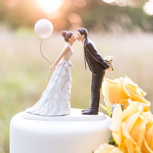 bride and groom figures kissing on top of wedding cake