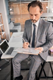 handsome-man-writing-on-clipboard-at-work