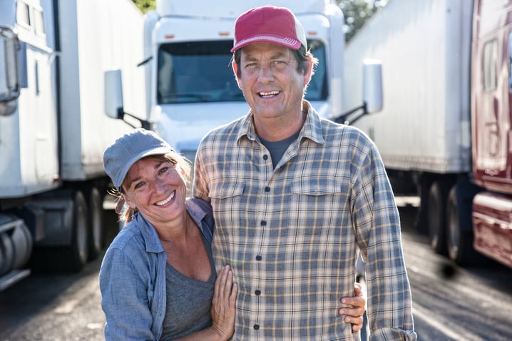 husband-and-wife-driving-team-in-front-of-their-truck